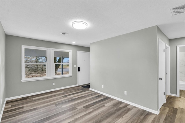 unfurnished room with dark hardwood / wood-style flooring and a textured ceiling