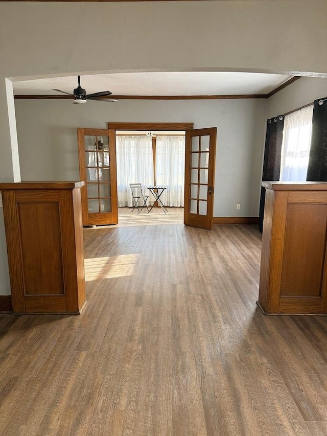 unfurnished living room featuring wood-type flooring, ornamental molding, french doors, and ceiling fan