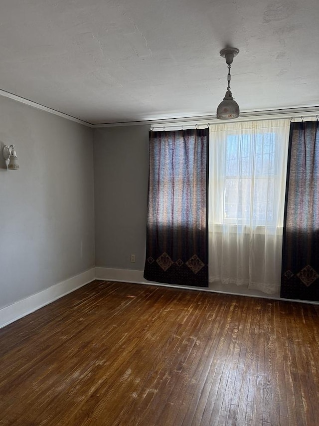 empty room with crown molding and dark wood-type flooring