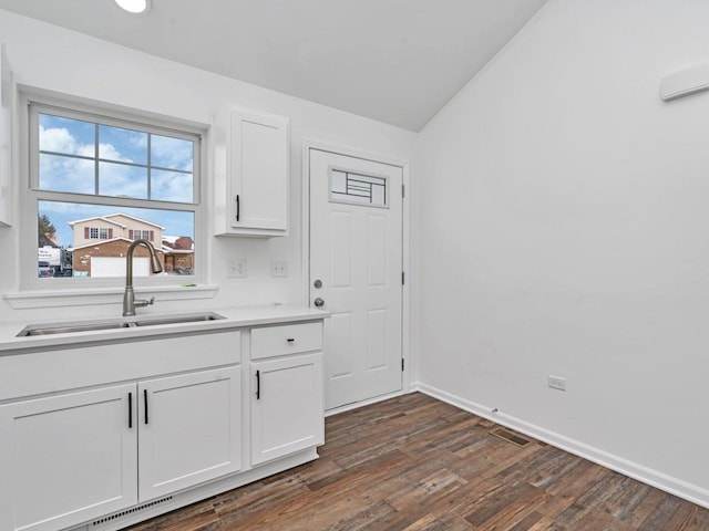 kitchen with lofted ceiling, sink, dark wood-type flooring, and white cabinets