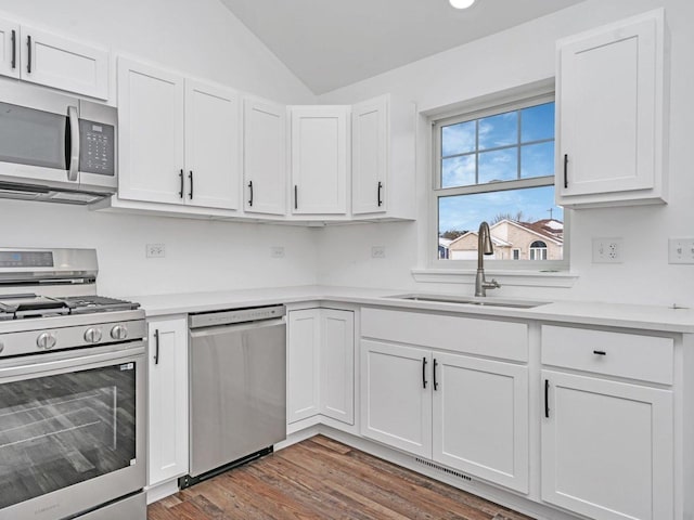 kitchen with dark wood-type flooring, lofted ceiling, sink, stainless steel appliances, and white cabinets