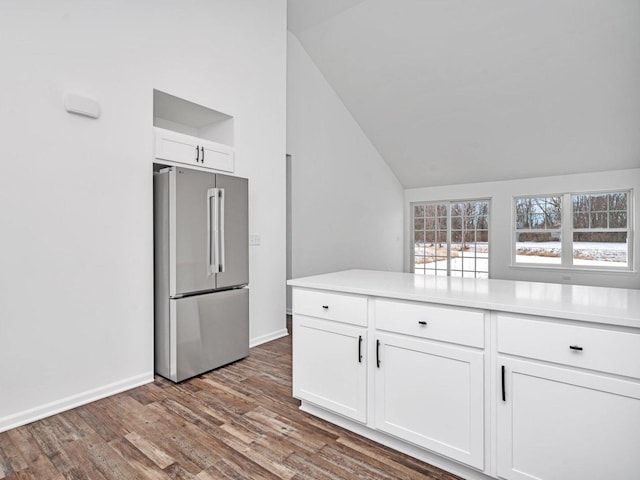 kitchen with lofted ceiling, high end fridge, light hardwood / wood-style flooring, and white cabinets