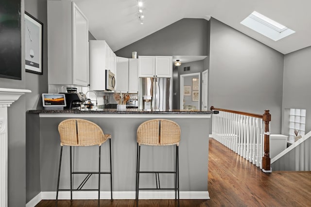 kitchen featuring stainless steel appliances, a breakfast bar, kitchen peninsula, and white cabinets