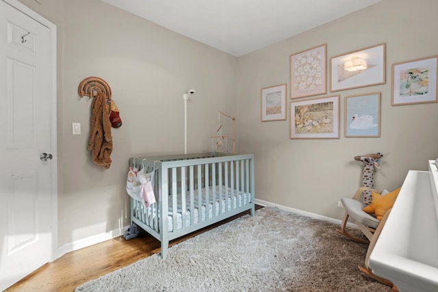 bedroom with a crib and hardwood / wood-style floors