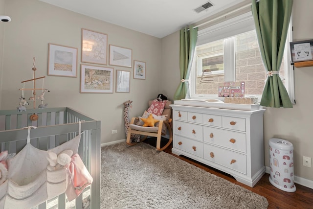 bedroom featuring dark wood-type flooring and a crib