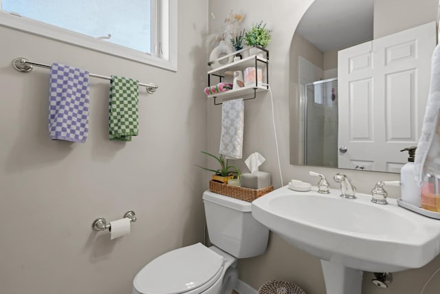 bathroom featuring sink, a shower with door, and toilet