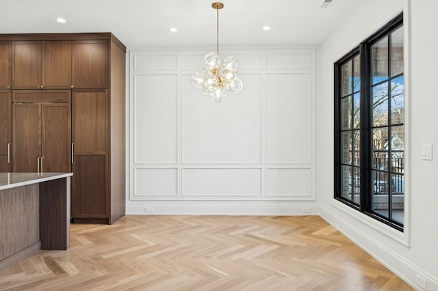 unfurnished dining area with light parquet flooring and a notable chandelier