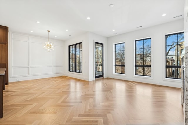 empty room with an inviting chandelier and light parquet flooring