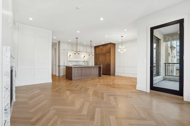 kitchen with a premium fireplace, a kitchen island, hanging light fixtures, and light parquet floors