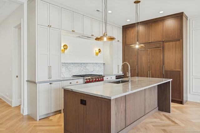 kitchen with sink, white cabinetry, pendant lighting, a large island, and light parquet floors