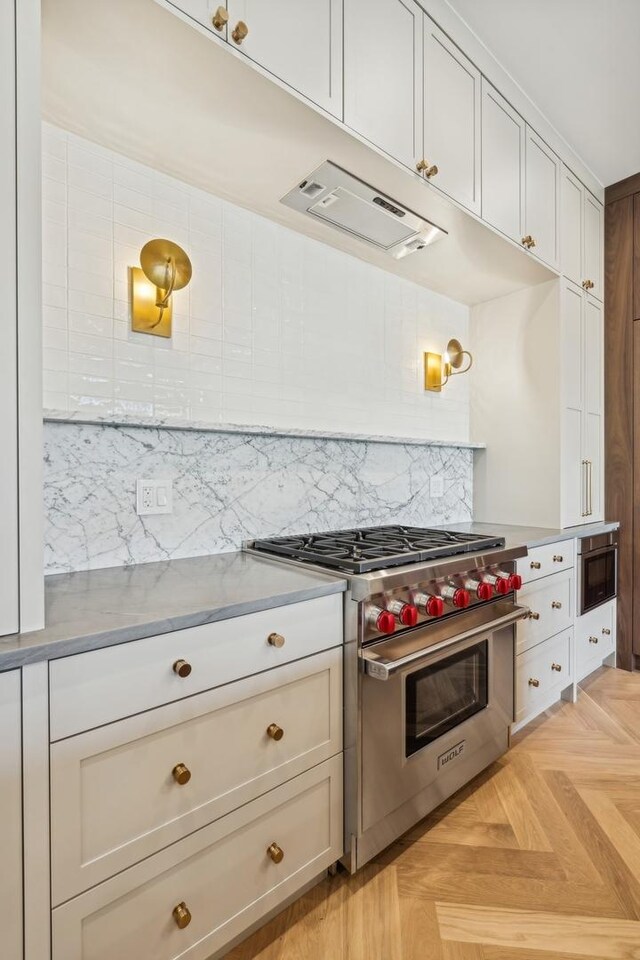 kitchen featuring tasteful backsplash, luxury stove, range hood, and light parquet flooring