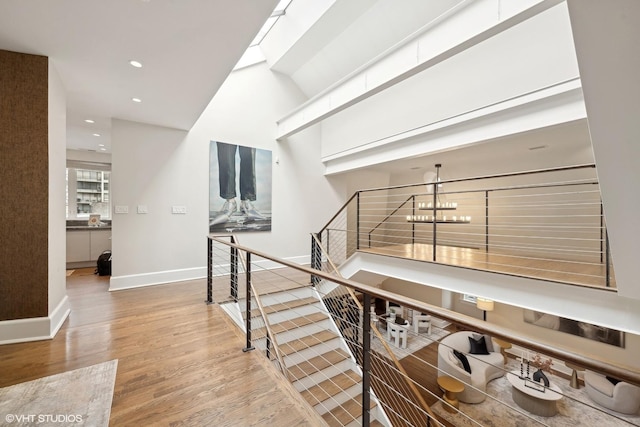 corridor with baseboards, wood finished floors, an inviting chandelier, an upstairs landing, and recessed lighting