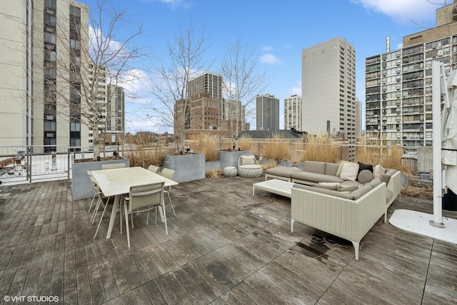 wooden terrace with outdoor dining area, a city view, and an outdoor living space