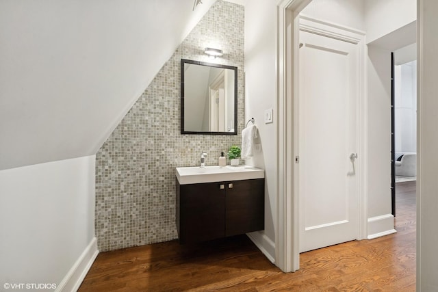 bathroom with lofted ceiling, tile walls, wood finished floors, and vanity