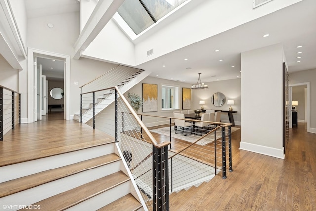 stairs featuring recessed lighting, a towering ceiling, wood finished floors, a chandelier, and baseboards