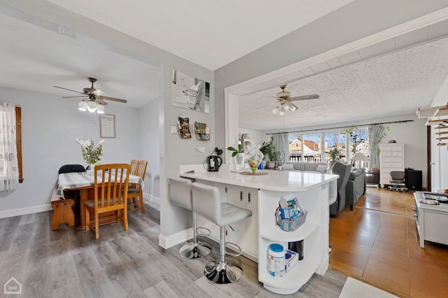 kitchen with baseboards, light countertops, a peninsula, and white cabinets