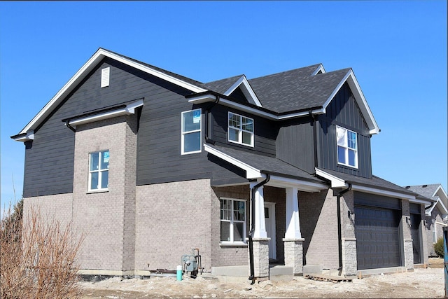 view of front of house featuring brick siding, board and batten siding, an attached garage, and roof with shingles