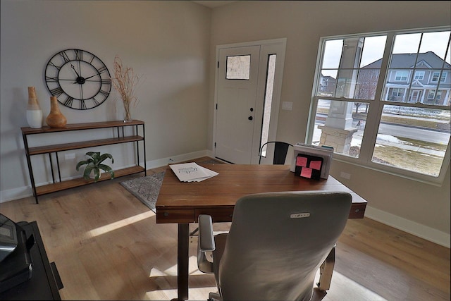 office area featuring a wealth of natural light, light wood-type flooring, and baseboards