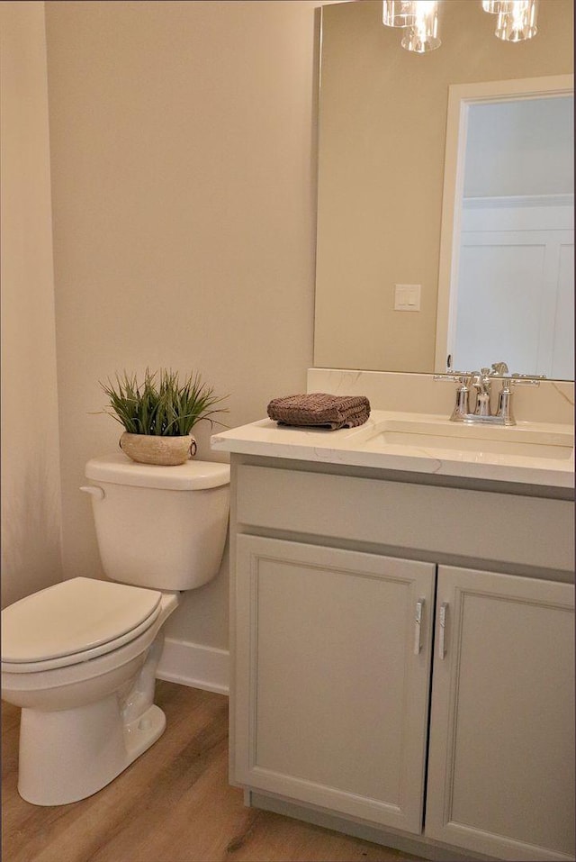 bathroom with a chandelier, toilet, wood finished floors, and vanity