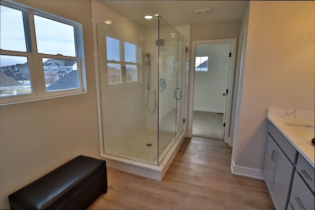 bathroom featuring visible vents, baseboards, a stall shower, wood finished floors, and vanity