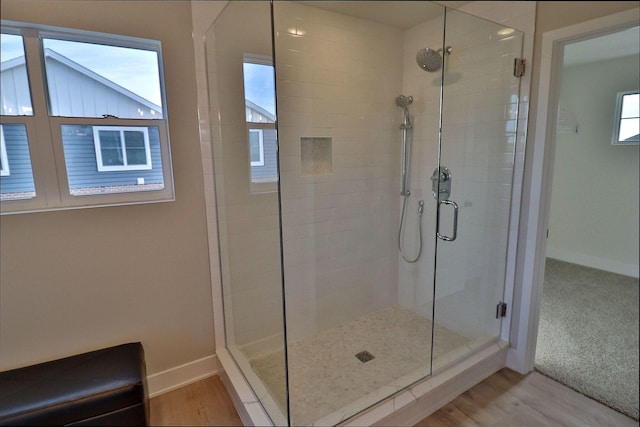 bathroom with a stall shower, baseboards, and wood finished floors