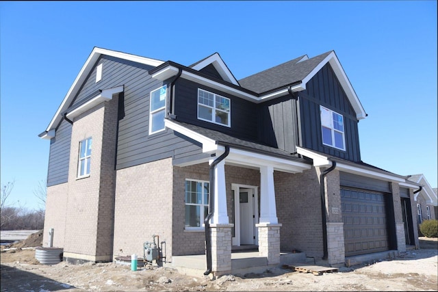 view of front of home with a garage, brick siding, board and batten siding, and covered porch