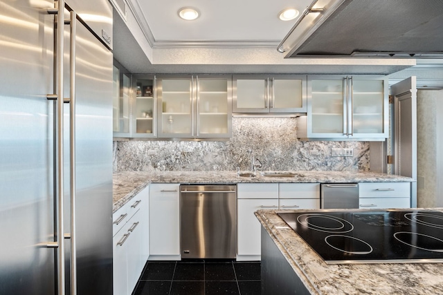 kitchen featuring tasteful backsplash, white cabinetry, sink, light stone counters, and stainless steel appliances