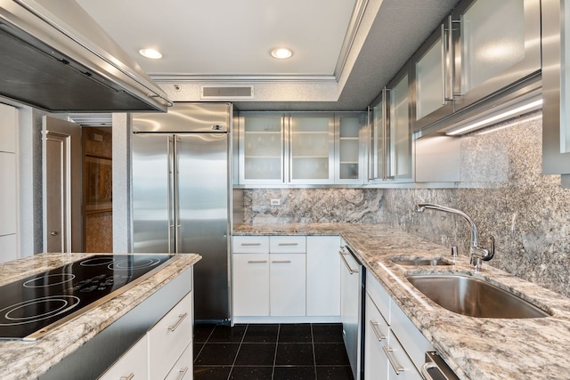 kitchen with white cabinetry, black electric stovetop, light stone counters, and sink