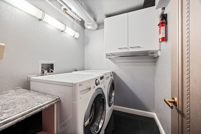 washroom with cabinets, washer and dryer, and dark tile patterned floors