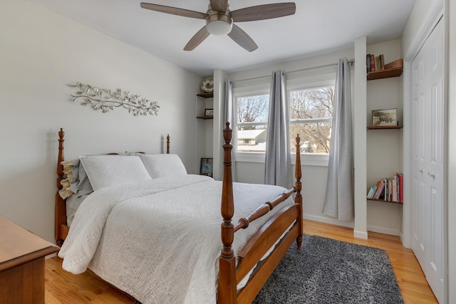 bedroom with a closet, ceiling fan, light wood-style flooring, and baseboards