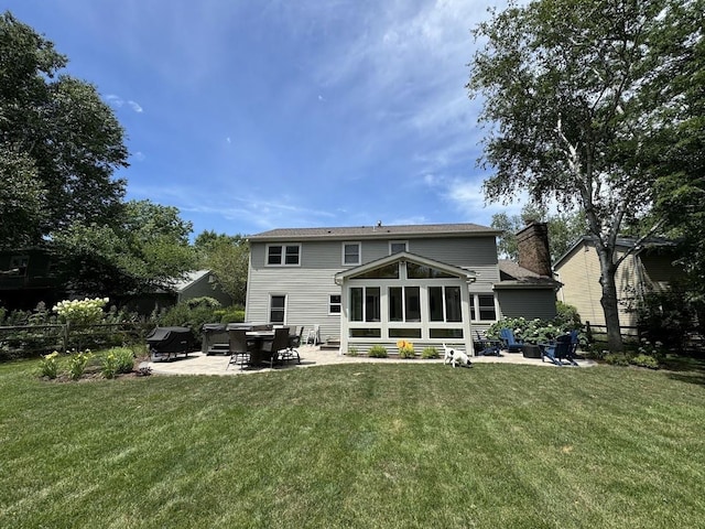 rear view of house with a patio, a lawn, fence, and a sunroom