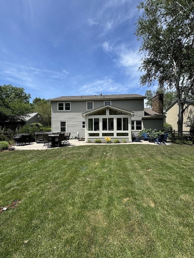 back of house with a patio, a yard, a chimney, and a sunroom