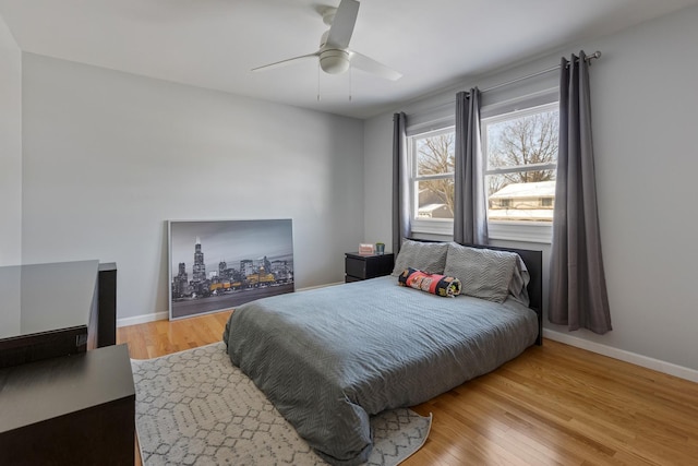 bedroom with ceiling fan, light wood-style flooring, and baseboards