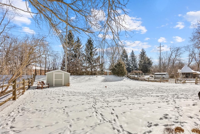 yard layered in snow with a storage shed, an outdoor structure, and fence