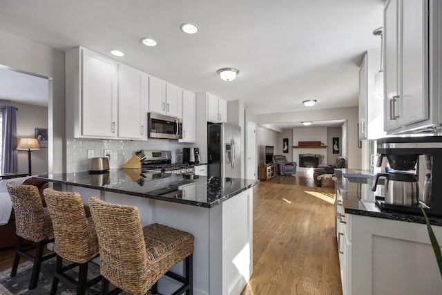 kitchen featuring white cabinets, appliances with stainless steel finishes, a breakfast bar, and open floor plan