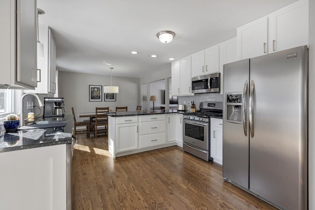 kitchen featuring dark wood-style floors, decorative light fixtures, a peninsula, stainless steel appliances, and white cabinetry