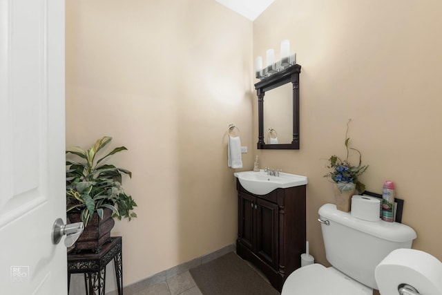 half bathroom featuring toilet, tile patterned flooring, baseboards, and vanity