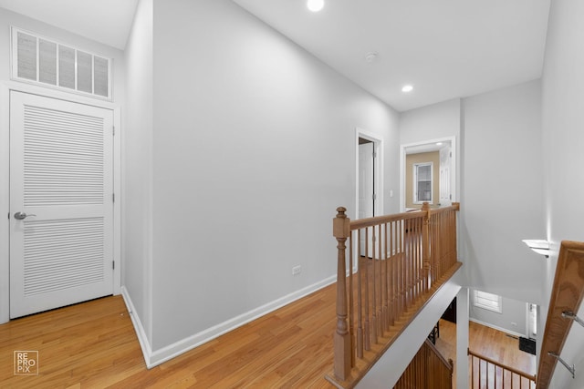 corridor with recessed lighting, visible vents, light wood-style floors, an upstairs landing, and baseboards