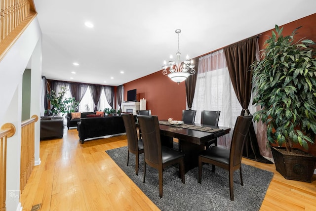 dining space featuring light wood-style floors, recessed lighting, a chandelier, and a fireplace