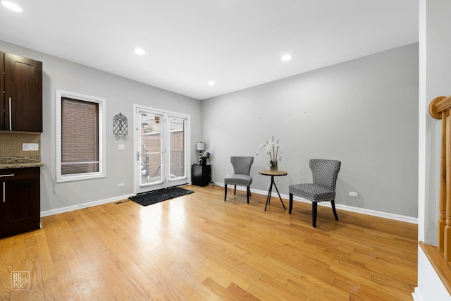 living area with light wood-type flooring, baseboards, and recessed lighting