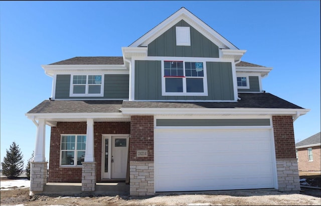 craftsman house featuring brick siding, board and batten siding, a shingled roof, and a garage