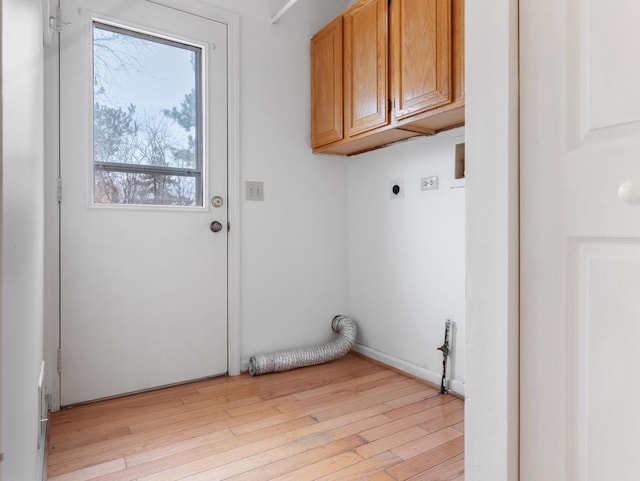 clothes washing area with cabinets, hookup for an electric dryer, and light wood-type flooring