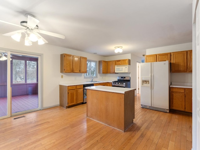 kitchen with sink, ceiling fan, stainless steel appliances, light hardwood / wood-style floors, and a kitchen island