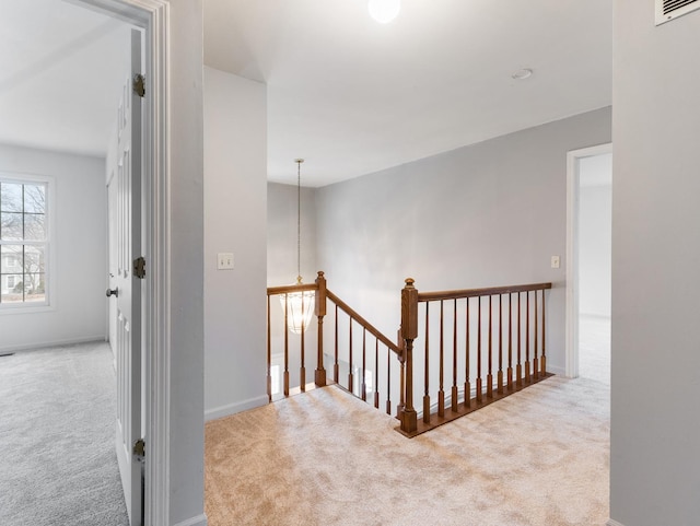 hallway featuring carpet floors and a notable chandelier