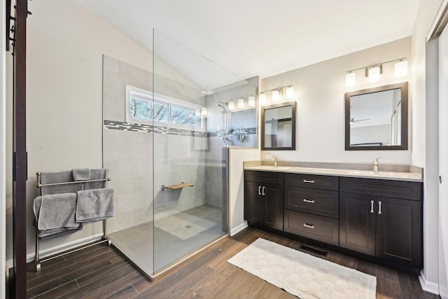 bathroom featuring vaulted ceiling, tiled shower, vanity, and wood-type flooring