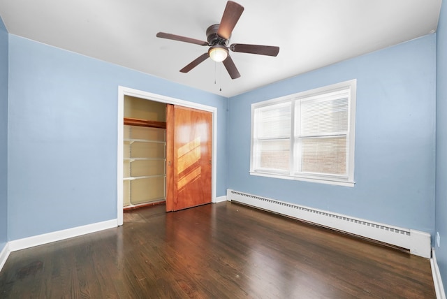 unfurnished bedroom with a baseboard heating unit, a closet, dark hardwood / wood-style floors, and ceiling fan