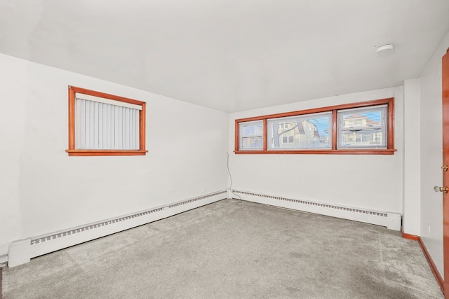 carpeted empty room featuring a baseboard heating unit