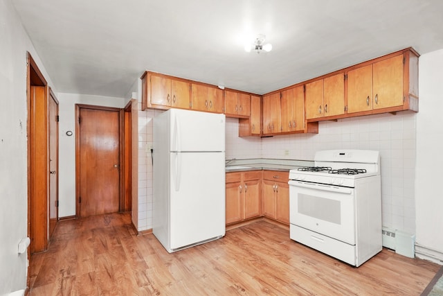 kitchen with tasteful backsplash, white appliances, and light hardwood / wood-style floors