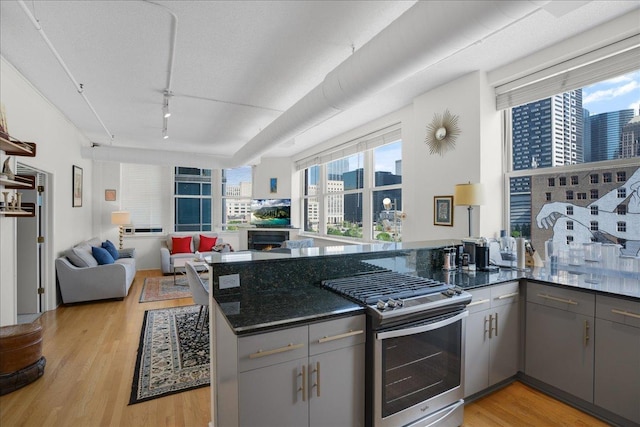 kitchen featuring gray cabinetry, plenty of natural light, light hardwood / wood-style floors, gas stove, and kitchen peninsula