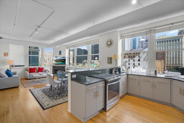 kitchen featuring gray cabinets, stainless steel range with gas cooktop, light wood-type flooring, and kitchen peninsula